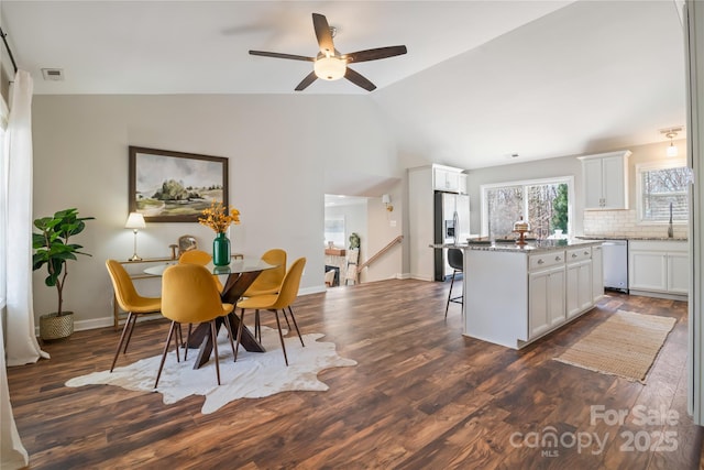 dining room featuring visible vents, baseboards, vaulted ceiling, and dark wood-type flooring