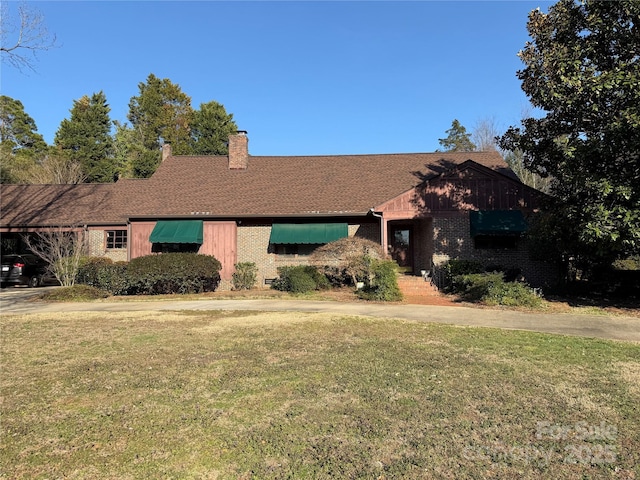 view of front facade featuring a front lawn, a chimney, and brick siding