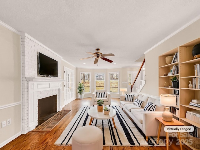 living room with ornamental molding, a brick fireplace, hardwood / wood-style floors, and a textured ceiling