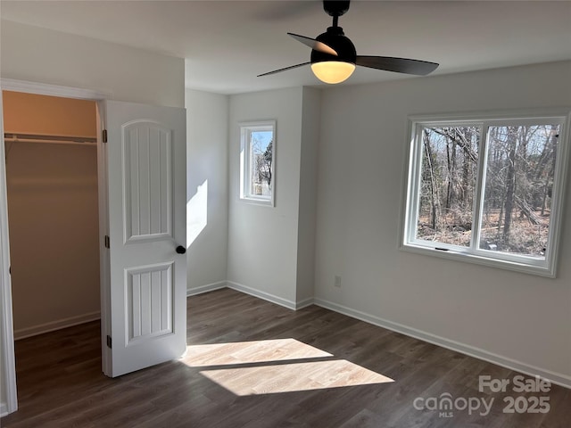 unfurnished bedroom with ceiling fan, dark hardwood / wood-style flooring, a closet, and a spacious closet