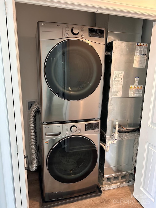 clothes washing area featuring stacked washer / dryer and light hardwood / wood-style floors