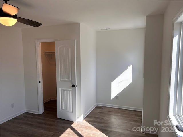 unfurnished bedroom with ceiling fan, a spacious closet, dark hardwood / wood-style floors, and a closet