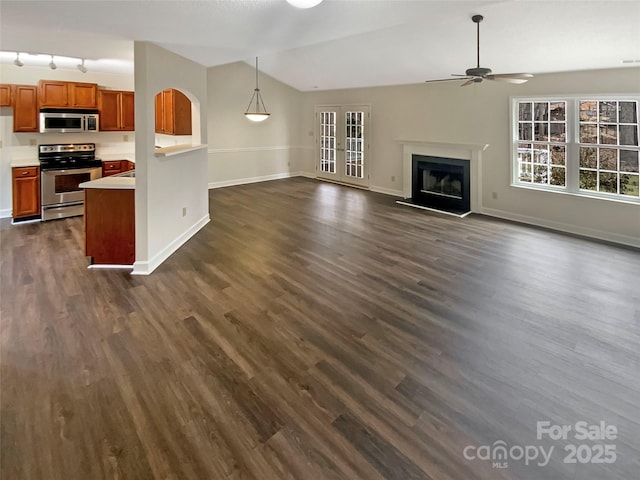 unfurnished living room with dark wood-type flooring, french doors, vaulted ceiling, track lighting, and ceiling fan