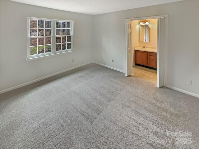 unfurnished bedroom featuring connected bathroom, sink, and light carpet