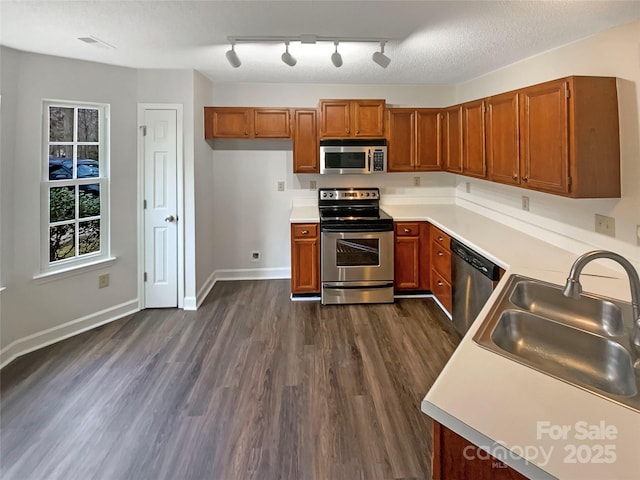 kitchen with dark wood-type flooring, appliances with stainless steel finishes, sink, and a textured ceiling