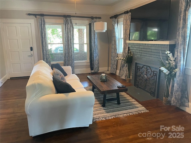 living room with dark hardwood / wood-style flooring and a brick fireplace