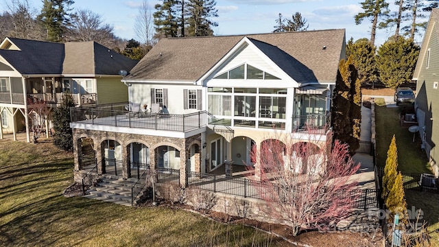 back of house with a balcony, a sunroom, a yard, and a patio area