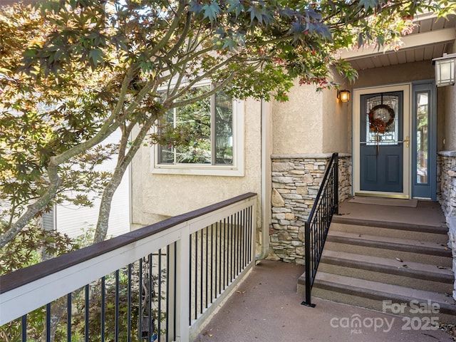 view of exterior entry featuring stone siding and stucco siding