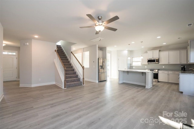 kitchen featuring white cabinetry, light wood-type flooring, appliances with stainless steel finishes, ceiling fan, and backsplash