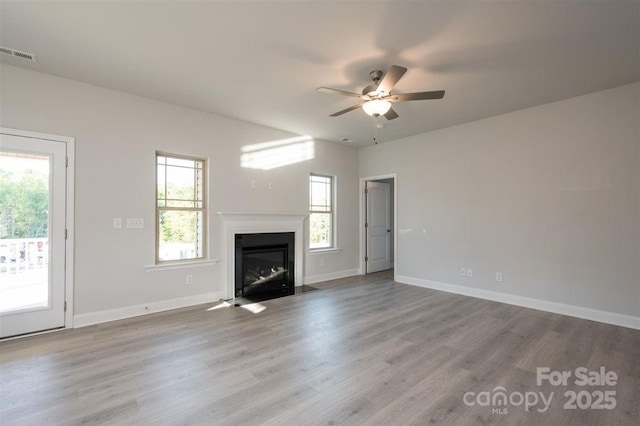 unfurnished living room featuring ceiling fan, a healthy amount of sunlight, and light wood-type flooring