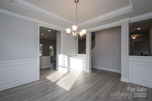 unfurnished dining area featuring hardwood / wood-style flooring, ornamental molding, and a raised ceiling