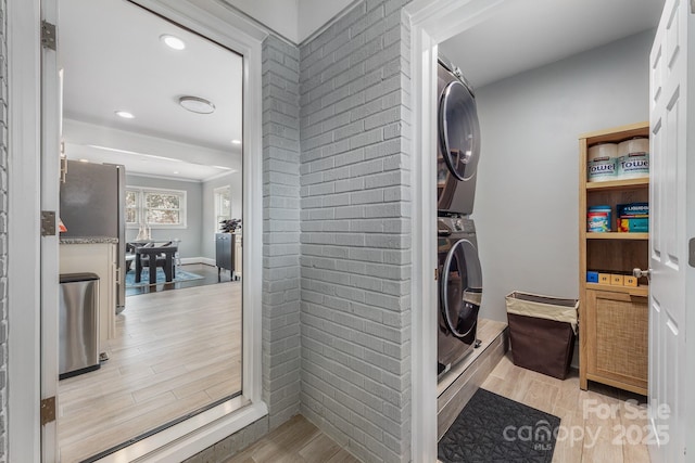 washroom featuring stacked washing maching and dryer and light hardwood / wood-style floors