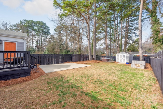 view of yard featuring a patio, a wooden deck, and a storage unit