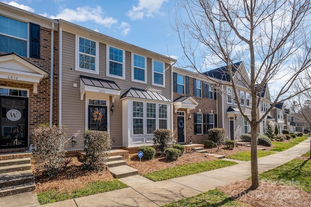 townhome / multi-family property with brick siding, a standing seam roof, metal roof, and a residential view