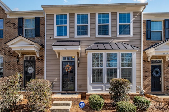 multi unit property with brick siding, metal roof, and a standing seam roof