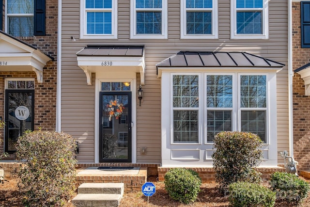 entrance to property featuring metal roof, a standing seam roof, and brick siding