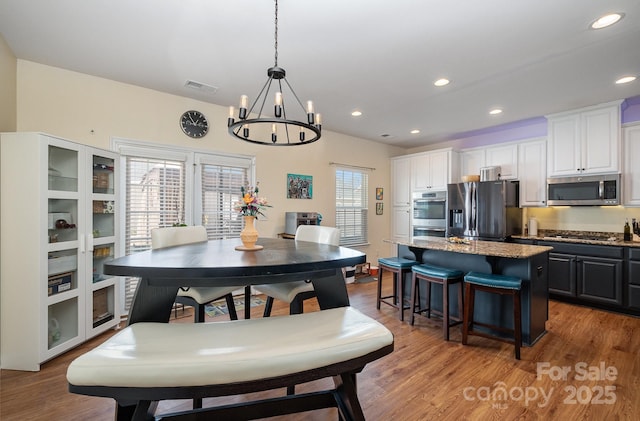 dining area featuring a notable chandelier, visible vents, recessed lighting, and light wood-style flooring