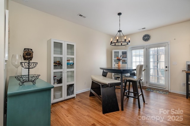 dining room with baseboards, a notable chandelier, wood finished floors, and visible vents