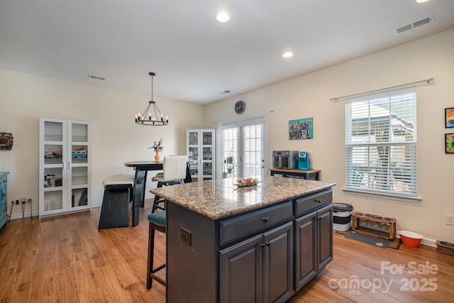 kitchen featuring pendant lighting, light wood-type flooring, visible vents, a breakfast bar area, and a kitchen island