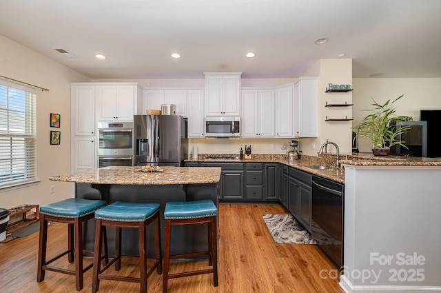 kitchen with a peninsula, stainless steel appliances, white cabinetry, and a sink