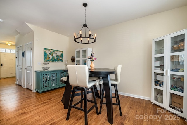 dining area featuring a notable chandelier, baseboards, and light wood-style flooring