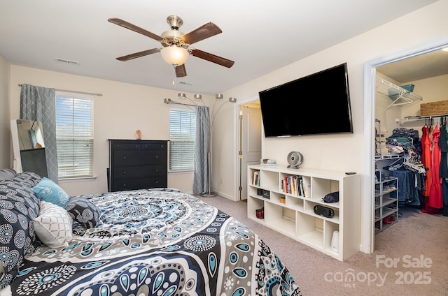 bedroom with light colored carpet, a closet, ceiling fan, visible vents, and a walk in closet