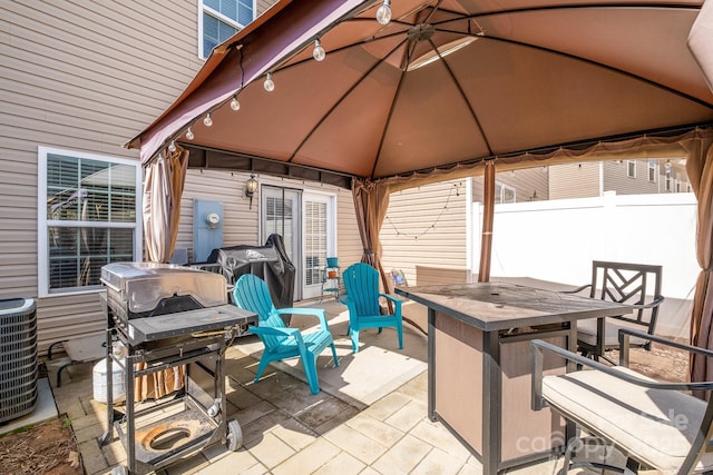 view of patio / terrace with a gazebo, fence, outdoor dining space, and cooling unit