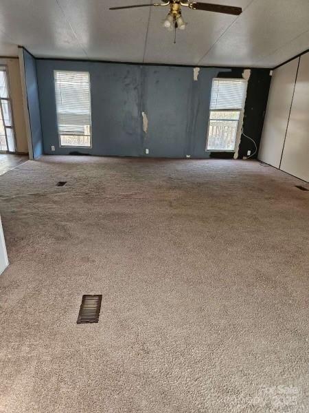 unfurnished living room with ceiling fan and carpet flooring