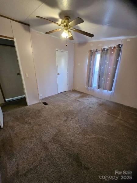 unfurnished bedroom featuring dark colored carpet and ceiling fan