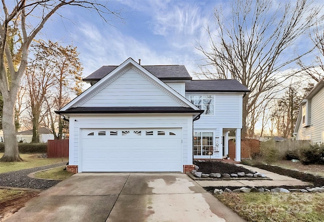 traditional-style home featuring a garage, concrete driveway, and fence