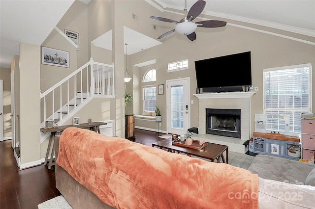 living area featuring ornamental molding, dark wood-style flooring, stairs, a fireplace, and high vaulted ceiling