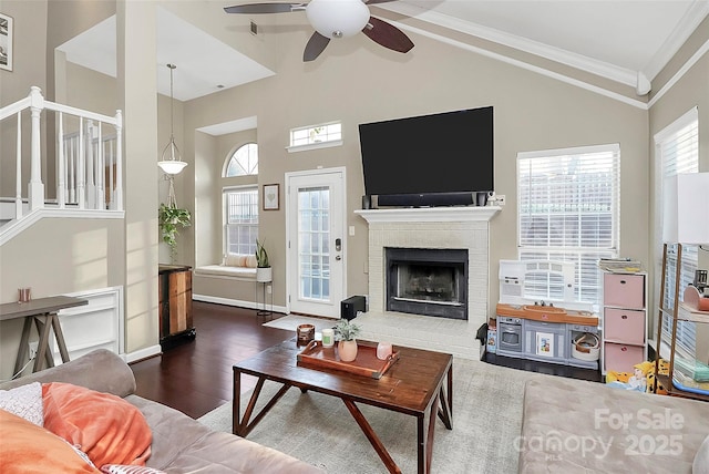 living room featuring dark wood-style floors, a wealth of natural light, a fireplace, and ornamental molding