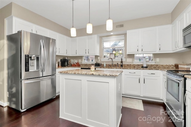 kitchen featuring pendant lighting, visible vents, appliances with stainless steel finishes, white cabinets, and a kitchen island