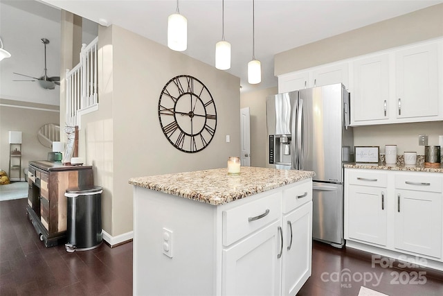 kitchen featuring light stone counters, a kitchen island, white cabinetry, stainless steel refrigerator with ice dispenser, and pendant lighting