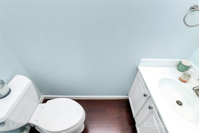 bathroom featuring baseboards, vanity, toilet, and wood finished floors