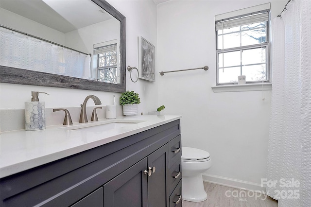 bathroom featuring toilet, baseboards, wood finished floors, and vanity