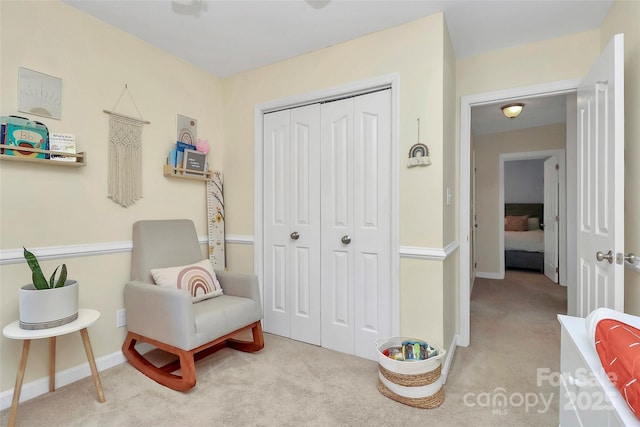 living area featuring light carpet and baseboards