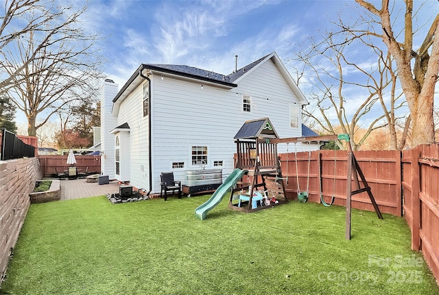 view of jungle gym with a fenced backyard, a lawn, and a patio