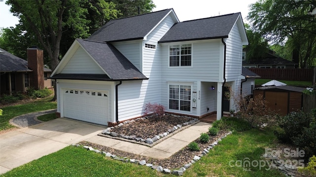 traditional-style home featuring a storage shed, concrete driveway, an attached garage, fence, and roof with shingles