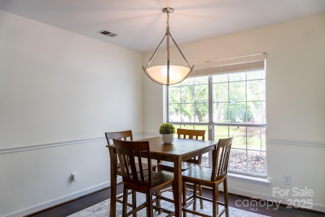 dining room featuring dark wood finished floors, visible vents, baseboards, and a healthy amount of sunlight