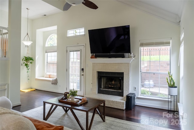 living area with high vaulted ceiling, a ceiling fan, wood finished floors, a brick fireplace, and visible vents