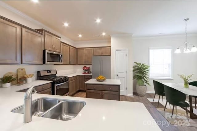 kitchen with pendant lighting, sink, dark wood-type flooring, appliances with stainless steel finishes, and a notable chandelier