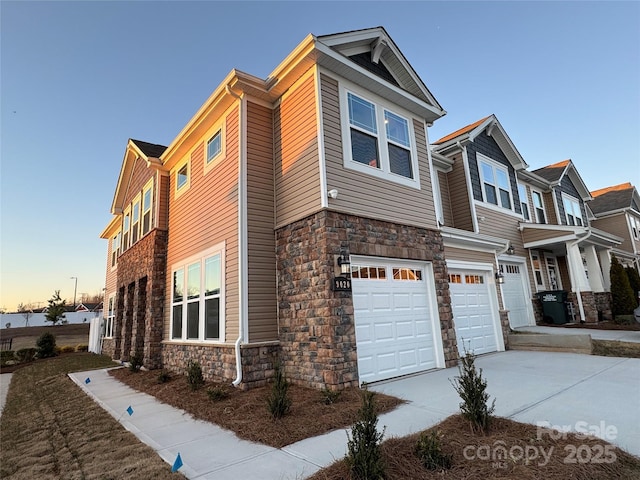 view of home's exterior with a garage, stone siding, and concrete driveway