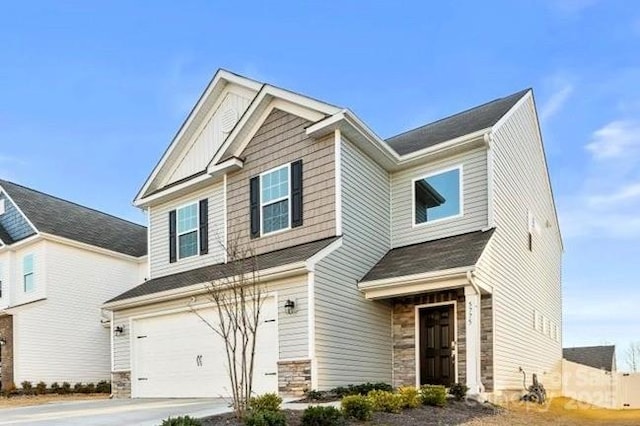 craftsman-style house with a garage, stone siding, and driveway