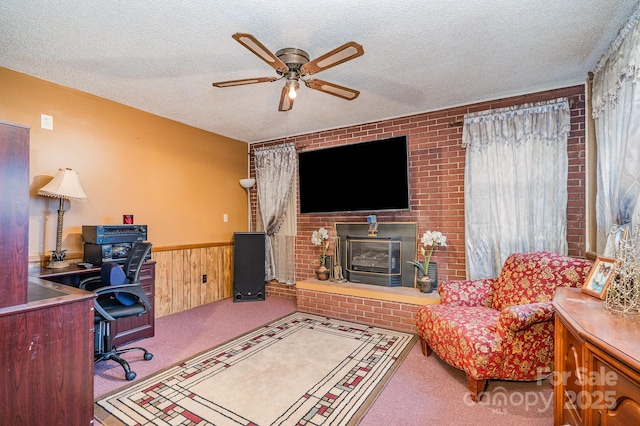 carpeted living room with ceiling fan, a textured ceiling, and wood walls