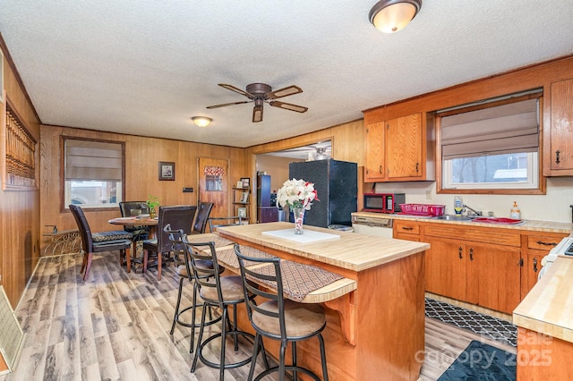 kitchen with dishwasher, a kitchen island, light wood-type flooring, and wood walls