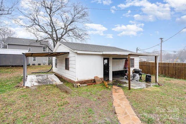 back of property featuring an outbuilding, a yard, and a carport