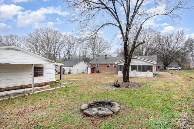 view of yard featuring an outdoor fire pit and a sunroom