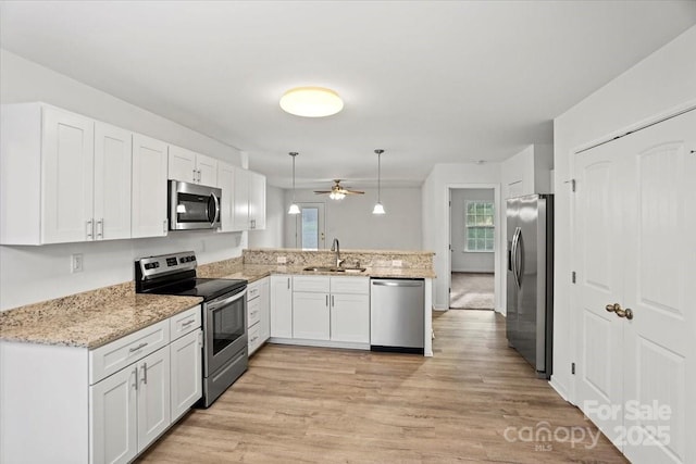 kitchen featuring sink, white cabinetry, appliances with stainless steel finishes, kitchen peninsula, and pendant lighting