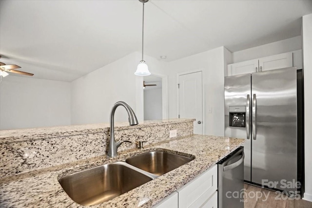 kitchen featuring pendant lighting, sink, white cabinetry, stainless steel appliances, and light stone countertops